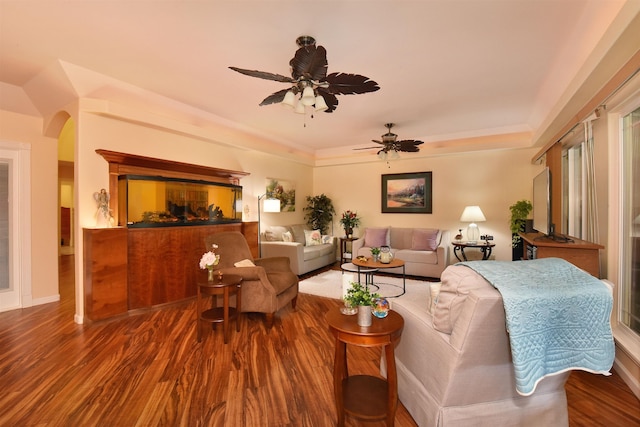 living room featuring arched walkways, a ceiling fan, and wood finished floors