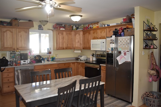 kitchen featuring appliances with stainless steel finishes, light countertops, a ceiling fan, and a sink