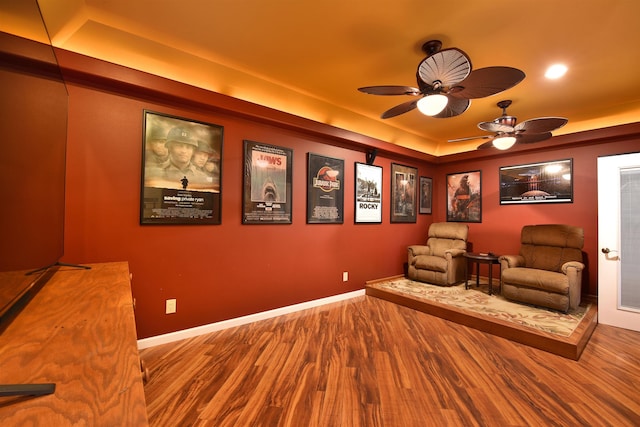 unfurnished room featuring a tray ceiling, wood finished floors, baseboards, and ceiling fan