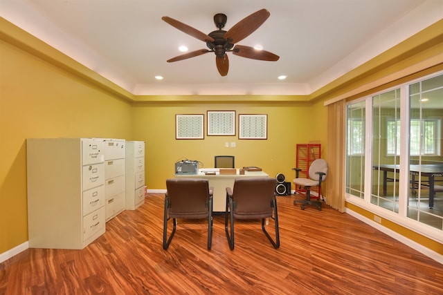 office space with a raised ceiling, wood finished floors, baseboards, and ceiling fan