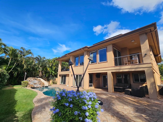 rear view of property featuring a balcony, a patio, and a lawn