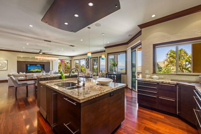 kitchen featuring a wealth of natural light, sink, a kitchen island with sink, and dark wood-type flooring