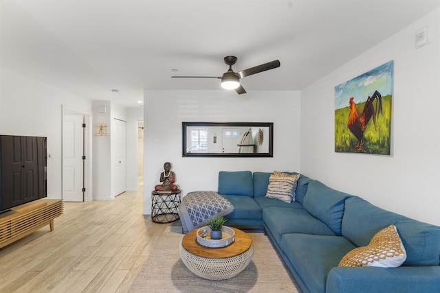 living area featuring light wood-type flooring, ceiling fan, and baseboards