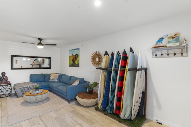 living room featuring wood finished floors, a ceiling fan, and baseboards