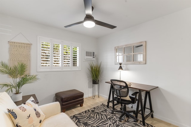 office space with a wall unit AC, wood finished floors, a ceiling fan, and baseboards