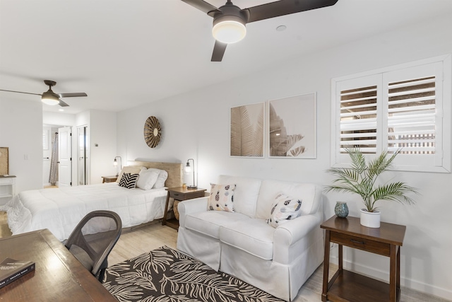 bedroom featuring a ceiling fan, baseboards, and light wood finished floors