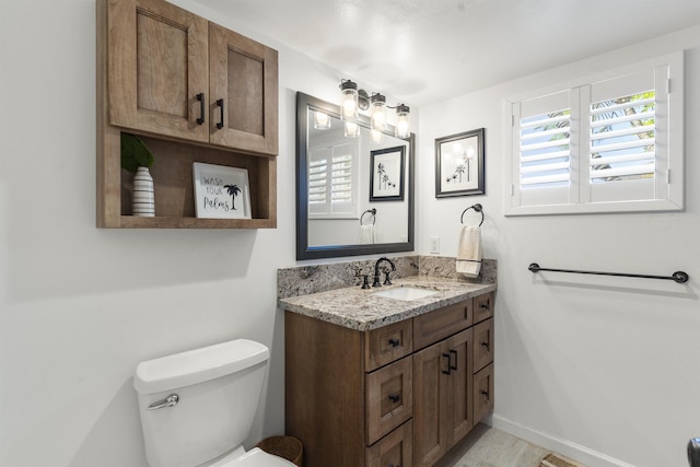 bathroom featuring vanity, toilet, and baseboards