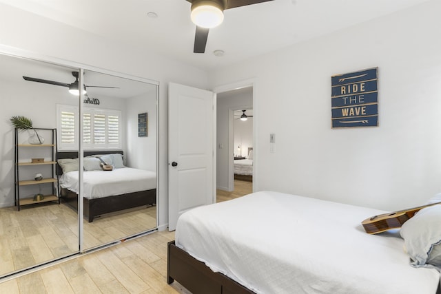 bedroom featuring ceiling fan, a closet, light wood-style flooring, and baseboards