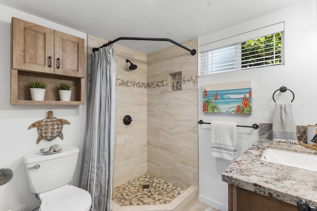 bathroom with a tile shower, vanity, and toilet