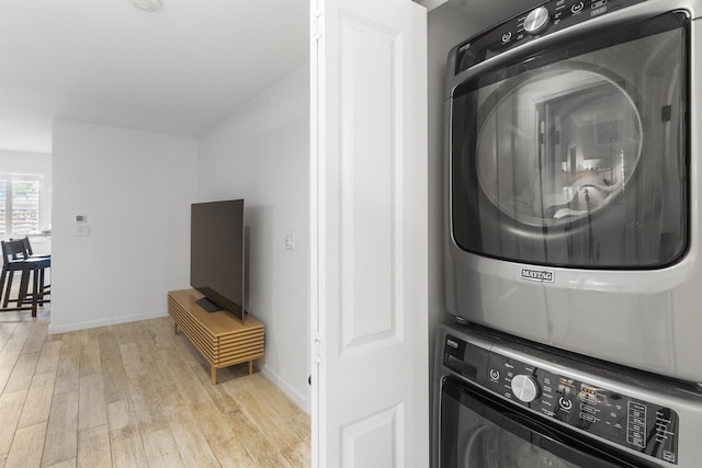 washroom with laundry area, baseboards, light wood finished floors, and stacked washer and clothes dryer