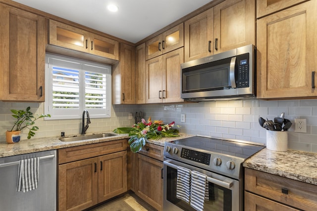 kitchen featuring appliances with stainless steel finishes, brown cabinets, a sink, and backsplash