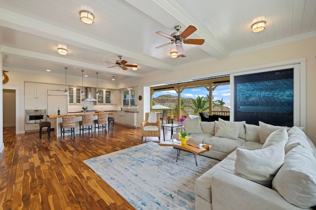 living room featuring dark wood-type flooring, ceiling fan, ornamental molding, and beamed ceiling