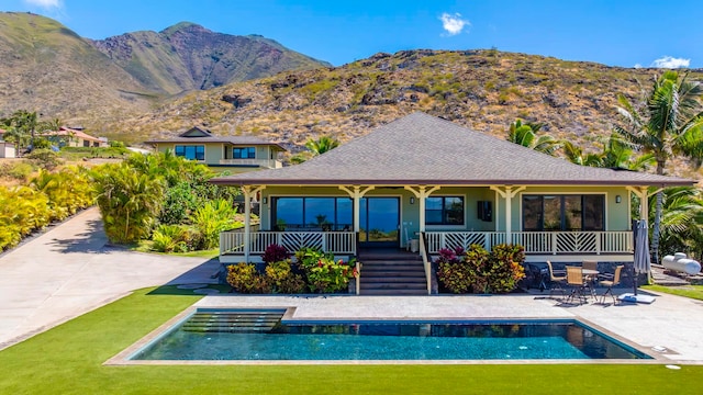 back of house with covered porch, a lawn, and a mountain view