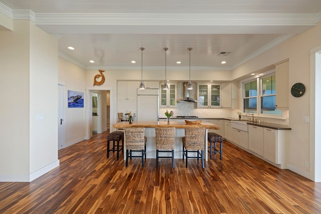 kitchen featuring dark hardwood / wood-style floors, wall chimney exhaust hood, paneled built in fridge, a center island, and decorative light fixtures