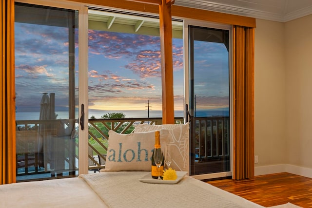 interior space featuring crown molding, wood finished floors, baseboards, and a water view