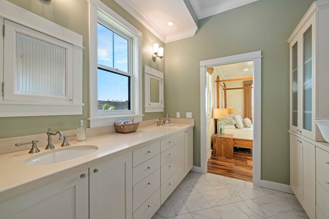 ensuite bathroom with a sink, double vanity, marble finish floor, and crown molding