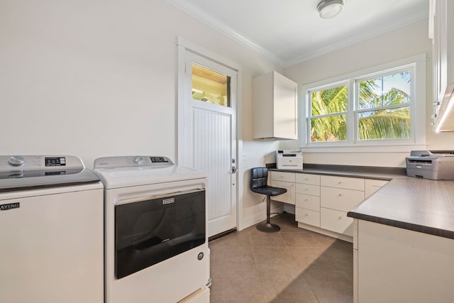 laundry room featuring ornamental molding, washing machine and dryer, cabinets, and dark tile patterned flooring