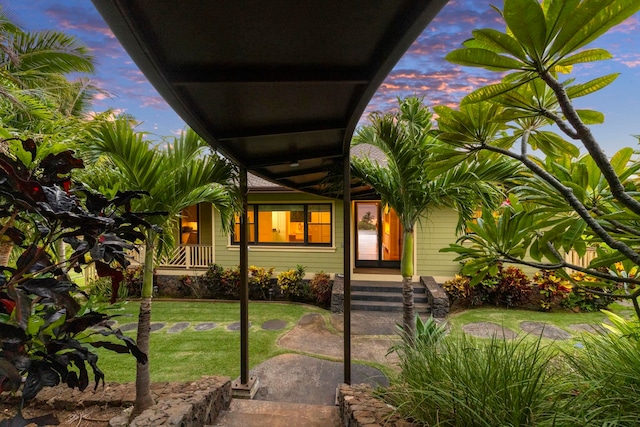 exterior entry at dusk featuring a lawn