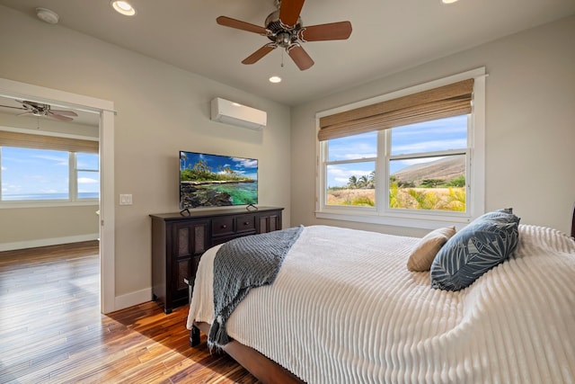 bedroom with light hardwood / wood-style flooring, ceiling fan, a wall mounted AC, and multiple windows