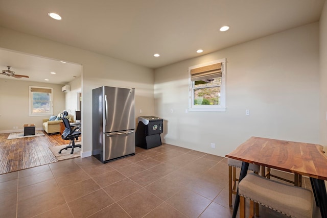 kitchen with a wall unit AC, stainless steel fridge, wood-type flooring, and ceiling fan