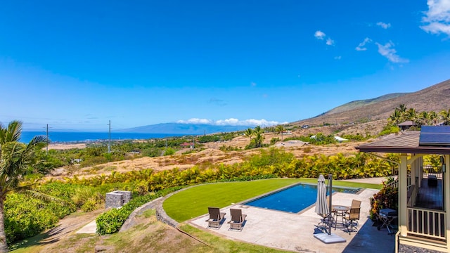 view of swimming pool featuring a mountain view, a patio area, and a lawn