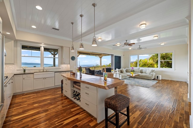 kitchen featuring crown molding, tasteful backsplash, butcher block counters, a sink, and dark wood-style floors