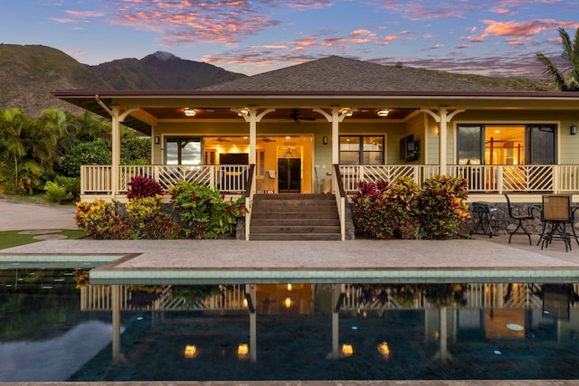 back house at dusk featuring a mountain view, a patio area, and ceiling fan