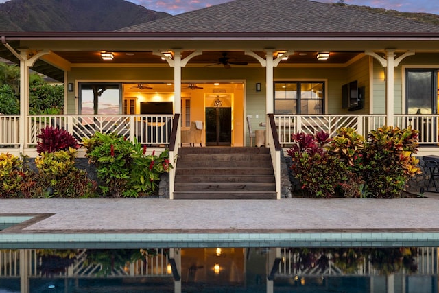 entrance to property featuring roof with shingles, a mountain view, an outdoor pool, a ceiling fan, and covered porch