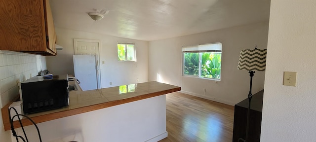 kitchen featuring vaulted ceiling, tile countertops, and light hardwood / wood-style floors