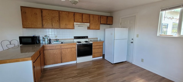 kitchen featuring white appliances, dark hardwood / wood-style floors, sink, and backsplash