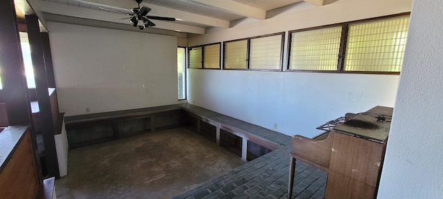 interior space featuring ceiling fan, concrete flooring, and beamed ceiling