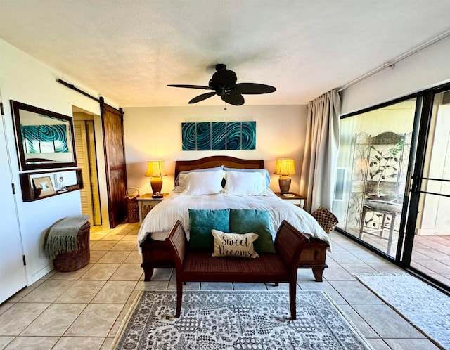 tiled bedroom with a barn door, ceiling fan, a textured ceiling, and access to outside