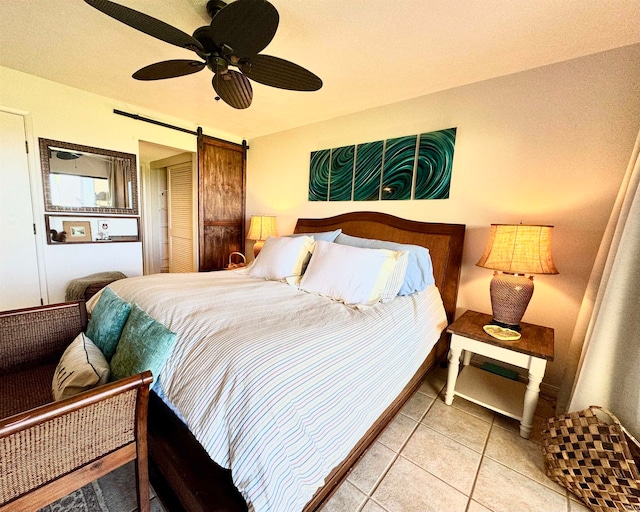 bedroom featuring a barn door, light tile patterned floors, and ceiling fan