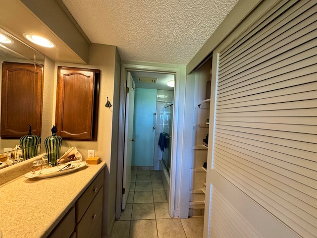 bathroom with vanity, a textured ceiling, tile patterned floors, and a shower with shower door