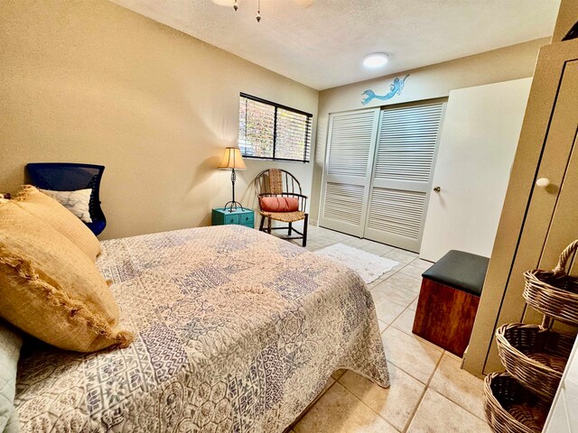 tiled bedroom with a textured ceiling and a closet