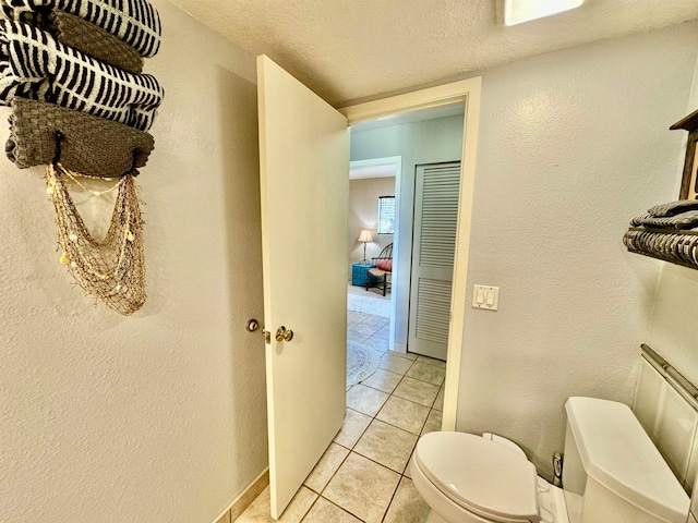 bathroom with toilet, a textured ceiling, and tile patterned floors