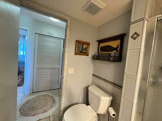 bathroom with tile patterned flooring, a textured ceiling, and toilet