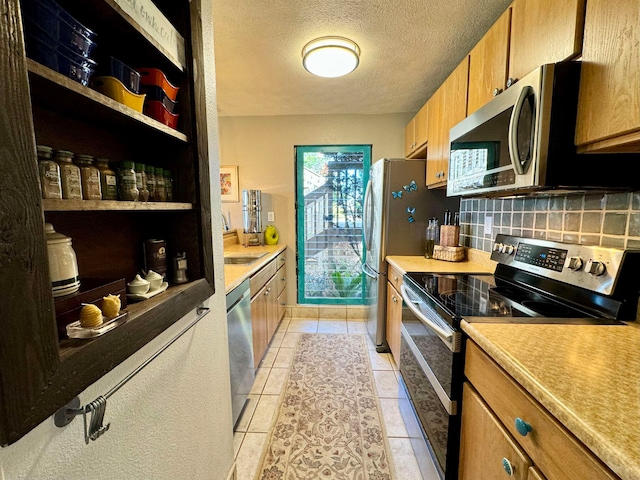 kitchen featuring stainless steel appliances, decorative backsplash, a textured ceiling, light tile patterned floors, and sink