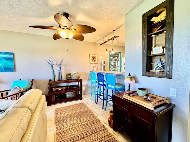 living room featuring ceiling fan, a textured ceiling, and light tile patterned flooring