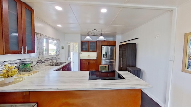 kitchen with black electric stovetop, sink, stainless steel fridge with ice dispenser, kitchen peninsula, and a barn door