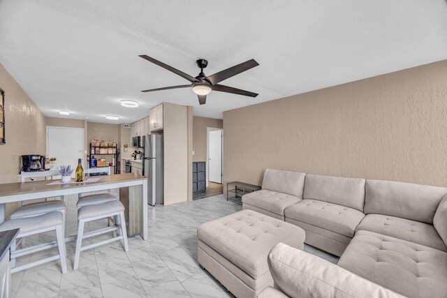 111 Kahului Beach Rd Unit D402, Kahului, HI 96732 - living area with a ceiling fan, a textured wall, and light marble finish floors