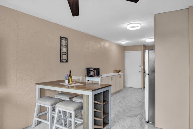 111 Kahului Beach Rd Unit D402, Kahului, HI 96732 - kitchen featuring freestanding refrigerator, light marble finish floors, a textured wall, and white cabinetry