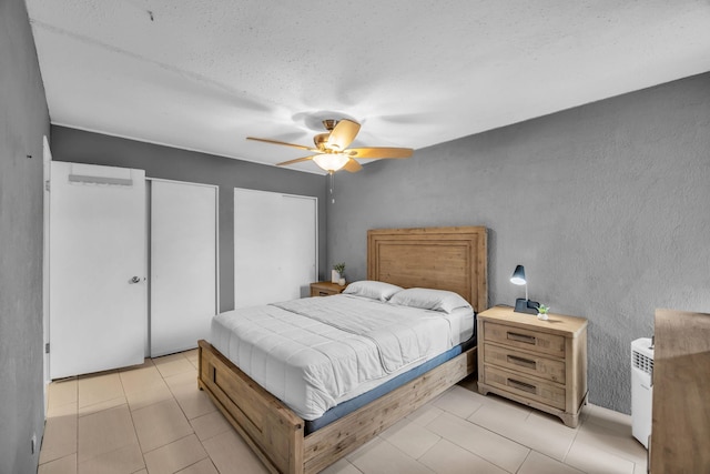 111 Kahului Beach Rd Unit D402, Kahului, HI 96732 - bedroom with a textured wall, a ceiling fan, two closets, light tile patterned floors, and a textured ceiling