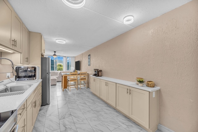 111 Kahului Beach Rd Unit D402, Kahului, HI 96732 - kitchen with freestanding refrigerator, a textured wall, light marble finish floors, light countertops, and a sink