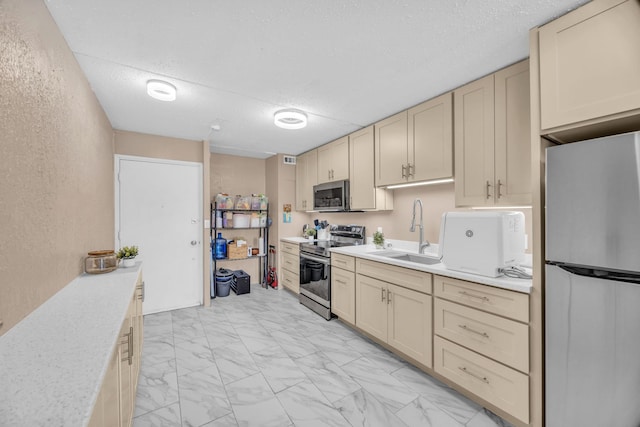 111 Kahului Beach Rd Unit D402, Kahului, HI 96732 - kitchen featuring appliances with stainless steel finishes, a sink, light countertops, light marble finish floors, and cream cabinetry