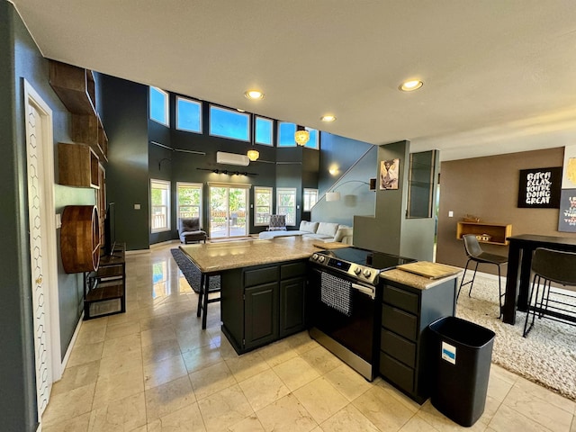 kitchen with electric range, a kitchen island, and a high ceiling