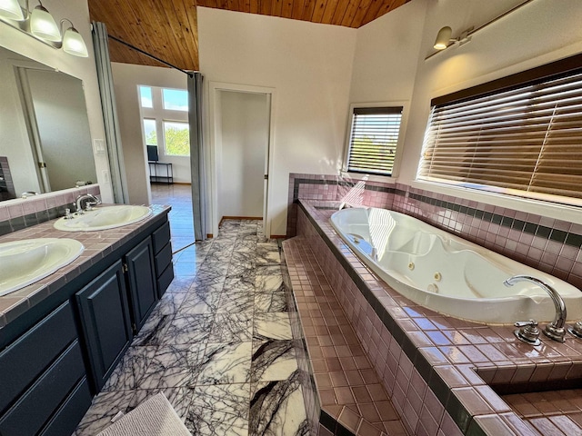 bathroom with wood ceiling, tiled tub, and vanity