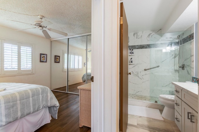 bedroom with a closet, dark hardwood / wood-style floors, a textured ceiling, and ceiling fan