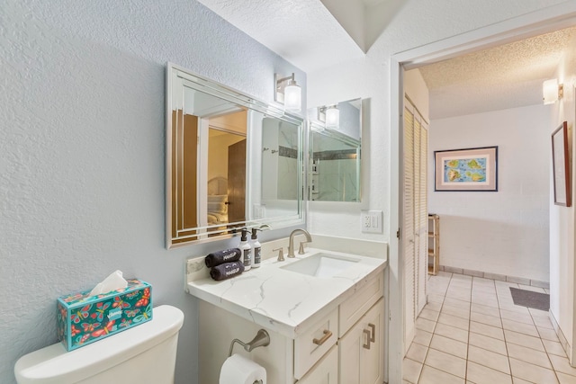 bathroom featuring vanity, tile patterned flooring, toilet, and a textured ceiling