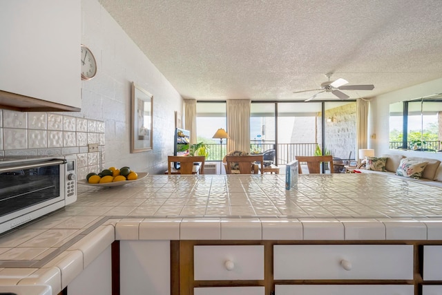 kitchen featuring ceiling fan, tile counters, a wealth of natural light, and a textured ceiling